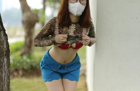 Asian brunette babe with a mask & glasses poses in her sexy outfit